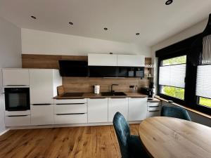 a kitchen with white cabinets and a table and chairs at Ferienwohnungen Heimatliebe in Ernst