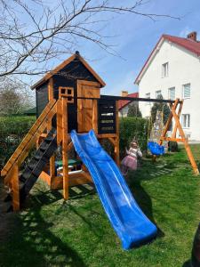 a playground with a slide and a house at Willa Kapitańska i Willa Marynarska in Łeba
