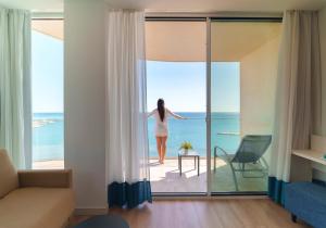 a woman standing on a balcony looking out at the ocean at Hotel Benalmadena Beach in Benalmádena