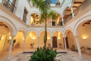 um corredor com uma palmeira num edifício em Casa del Rey Sabio em Sevilha