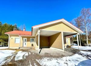 a yellow house with a garage in the snow at Apartment Isorannantie in Pyhäjoki