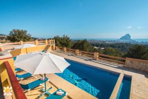 vista sulla piscina con ombrellone e sedie di Villa Niceview by Abahana Villas a Calpe