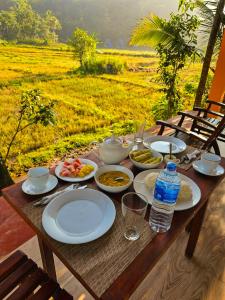 una mesa de madera con platos de comida en un campo en Sinharaja Cabana en Matara