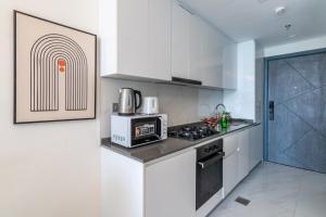 a white kitchen with a microwave and a stove at The Smart Concierge - Samana Hills in Dubai