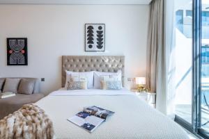 a bedroom with a large white bed and a window at The Smart Concierge - Samana Hills in Dubai