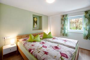 a bedroom with two beds with green pillows and a window at Ferienwohnung Birke in Altusried