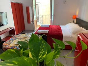 um quarto de hotel com uma cama e uma televisão e plantas em Guest house Le Sibille em Taormina