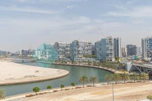 einen Fluss mit Palmen und Gebäuden in einer Stadt in der Unterkunft Spacious Studio In Thalassa in Abu Dhabi