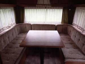 un sofá con una mesa frente a una ventana en Zážitkový pobyt v karavanu u Slezské Harty, 