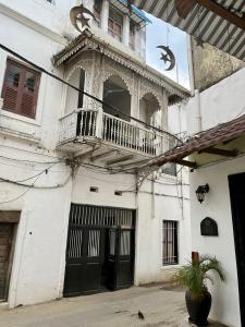 - un bâtiment blanc avec un balcon et une terrasse couverte dans l'établissement Balcony House, à Zanzibar City