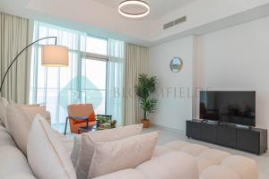 ein Wohnzimmer mit einem Sofa und einem TV in der Unterkunft Modern 1 Bedroom In Thalassa in Abu Dhabi