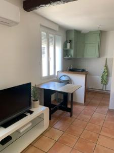 a kitchen with a table and a tv in a room at Studio cosy avec clim 33m2 in Aimargues