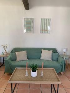 a living room with a green couch and a table at Studio cosy avec clim 33m2 in Aimargues
