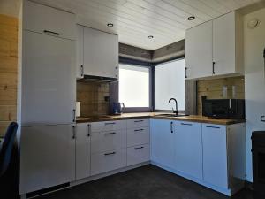 a kitchen with white cabinets and a large window at Domek nad jeziorem in Krasnopol