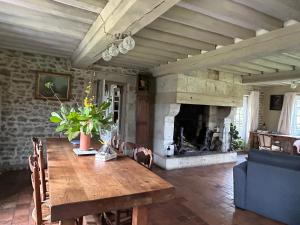 Les Hortensias في Manerbe: غرفة طعام مع طاولة ومدفأة