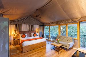 - une chambre dans une tente avec un lit et un canapé dans l'établissement Ayar Jungle Resort, à Nainital