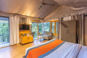 a bedroom with a bed and a desk and a television at Ayar Jungle Resort in Nainital