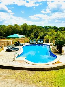 a large swimming pool with chairs and an umbrella at Finca Son Manxo (villas2meet Mallorca) in Manacor