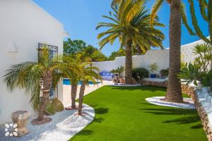 a courtyard with palm trees and a white building at Villa Tuvalu by Abahana Luxe in Moraira