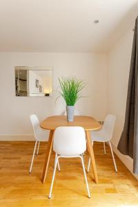 a dining room table with white chairs and a potted plant at Brand New Flat in Central London with Car Park in London