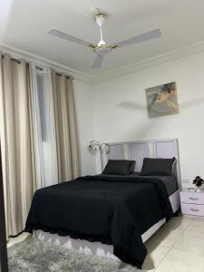 a bedroom with a black bed and a ceiling fan at Cozy Haven Suite in Accra