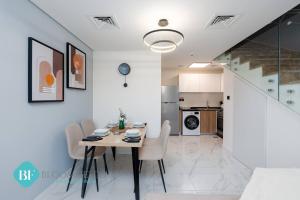 comedor y cocina con mesa y sillas en Premium 1 Br Duplex In Rukan, en Dubái