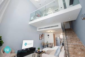 a living room with white furniture and a staircase at Premium 1 Br Duplex In Rukan in Dubai