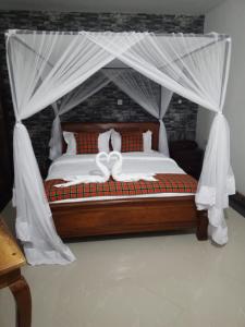 1 dormitorio con 1 cama con dosel en Queen's Way Resort en Kisumu