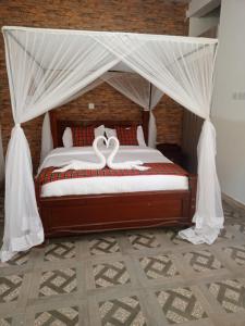 a bedroom with a canopy bed with white drapes at Queen's Way Resort in Kisumu
