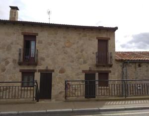 CardeñosaにあるCasa Rural El Caño Del Santoの石造りの建物で、2つのドアと2つのバルコニーが付いています。