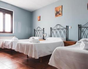 CardeñosaにあるCasa Rural El Caño Del Santoの白いシーツが備わるベッド3台、窓が付いた客室です。