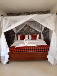 een slaapkamer met een hemelbed met 2 zwanen erop bij Queen's Way Resort in Kisumu