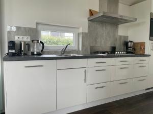 a kitchen with white cabinets and a sink at Holiday Home Ruisweg 51 by Interhome in Wemeldinge