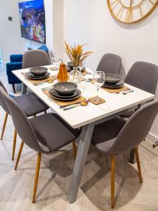 uma mesa de jantar com cadeiras, pratos e copos em Modern 4-Bed Townhouse, Conveniently Located Near Leeds City Centre - Perfect for Corporate Stays em Farnley