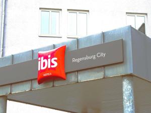 un cartello in cima a un edificio con un cartello di autobus di ibis Hotel Regensburg City a Ratisbona