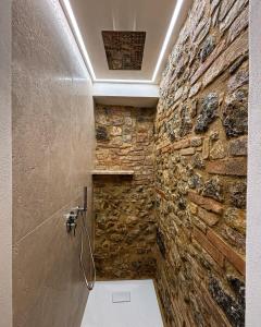 e bagno con parete in pietra e doccia. di Podere Bellavista a San Gimignano