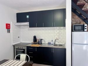 a kitchen with black cabinets and a white refrigerator at Traditional House in Curral das Freiras