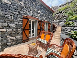 a patio with chairs and a table and a stone wall at Traditional House in Curral das Freiras