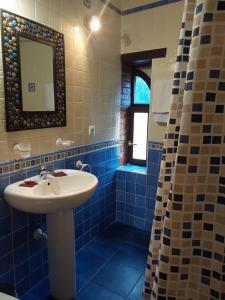 Baño de azulejos azules con lavabo y espejo en POSADA LAS MOZAS DEL AGUA DE GABY Y TINO, en Ríocorvo