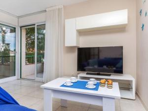 a living room with a white table and a tv at Apartment Mediterrani by Interhome in Llança