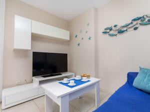 a living room with a white table and a tv at Apartment Mediterrani by Interhome in Llança +14 photos