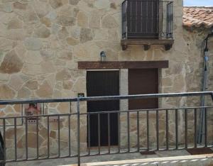 a building with a gate and a door with a balcony at Peña Caballera in Cardeñosa