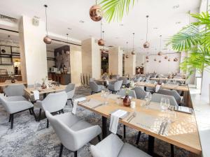 a restaurant with wooden tables and chairs at Mercure Opole in Opole