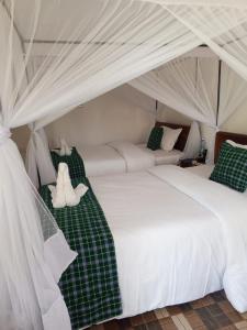 a bedroom with two beds with a teddy bear sitting on them at Queen's Way Resort in Kisumu