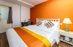 1 dormitorio con 1 cama grande y pared de color naranja en Xi'an See Tang Guesthouse, en Xi'an