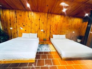 2 łóżka w pokoju z drewnianymi ścianami w obiekcie Lam Vien Garden Villa - Homestay Da Lat w mieście Da Lat