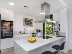 a white kitchen with a bowl of fruit on a counter at Holiday Home Sa Riera White on the Beach by Interhome in Begur