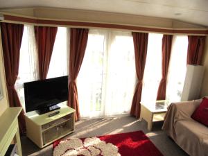 sala de estar con TV de pantalla plana y sofá en Sapphire 8 Berth panel heated Towervans en Sutton on Sea