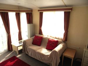 sala de estar con sofá y 2 almohadas rojas en Sapphire 8 Berth panel heated Towervans en Sutton on Sea