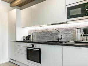 a white kitchen with white cabinets and a sink at Holiday Home Naava chalet 103 by Interhome in Ähtäri +14 photos